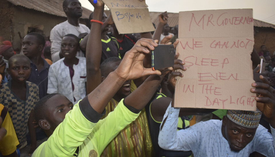 Människor samlas runt det område där beväpnade män kidnappade skolbarn i Chikun i Nigeria, torsdagen den 7 mars. ”Herr guvernör vi kan inte sova, inte ens under dagsljus” står det på skylten.